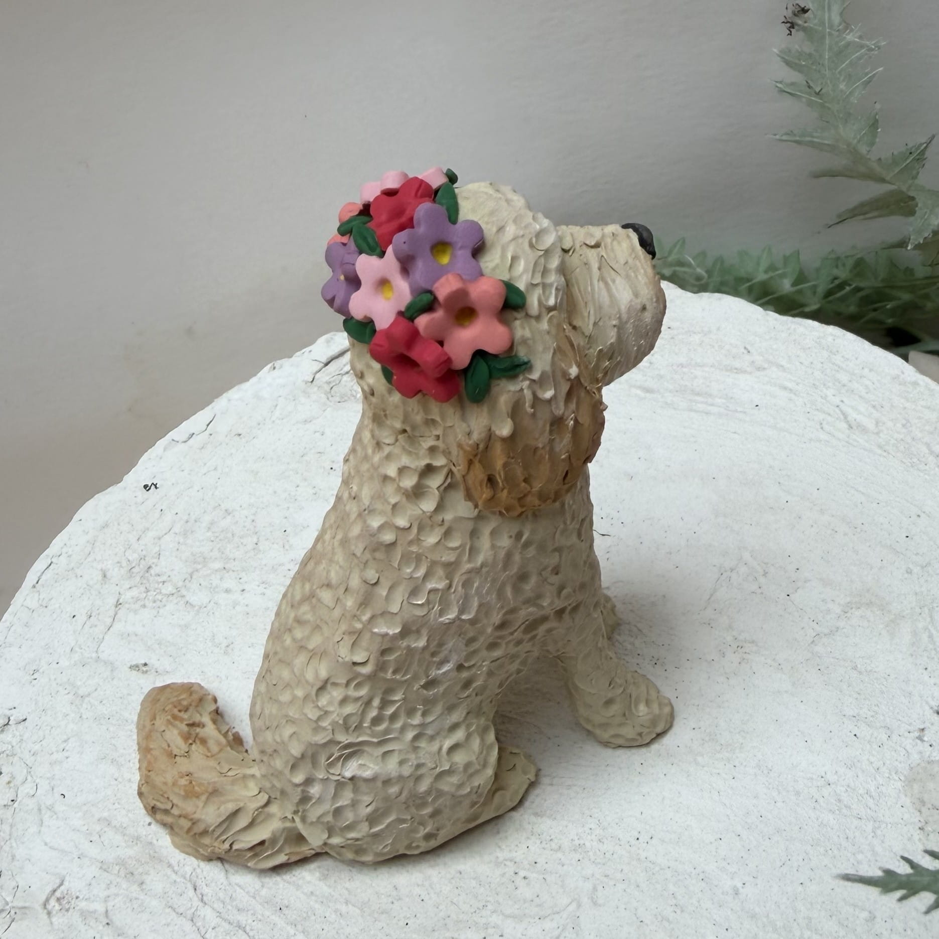 Dog figurine with a floral headband on a white surface