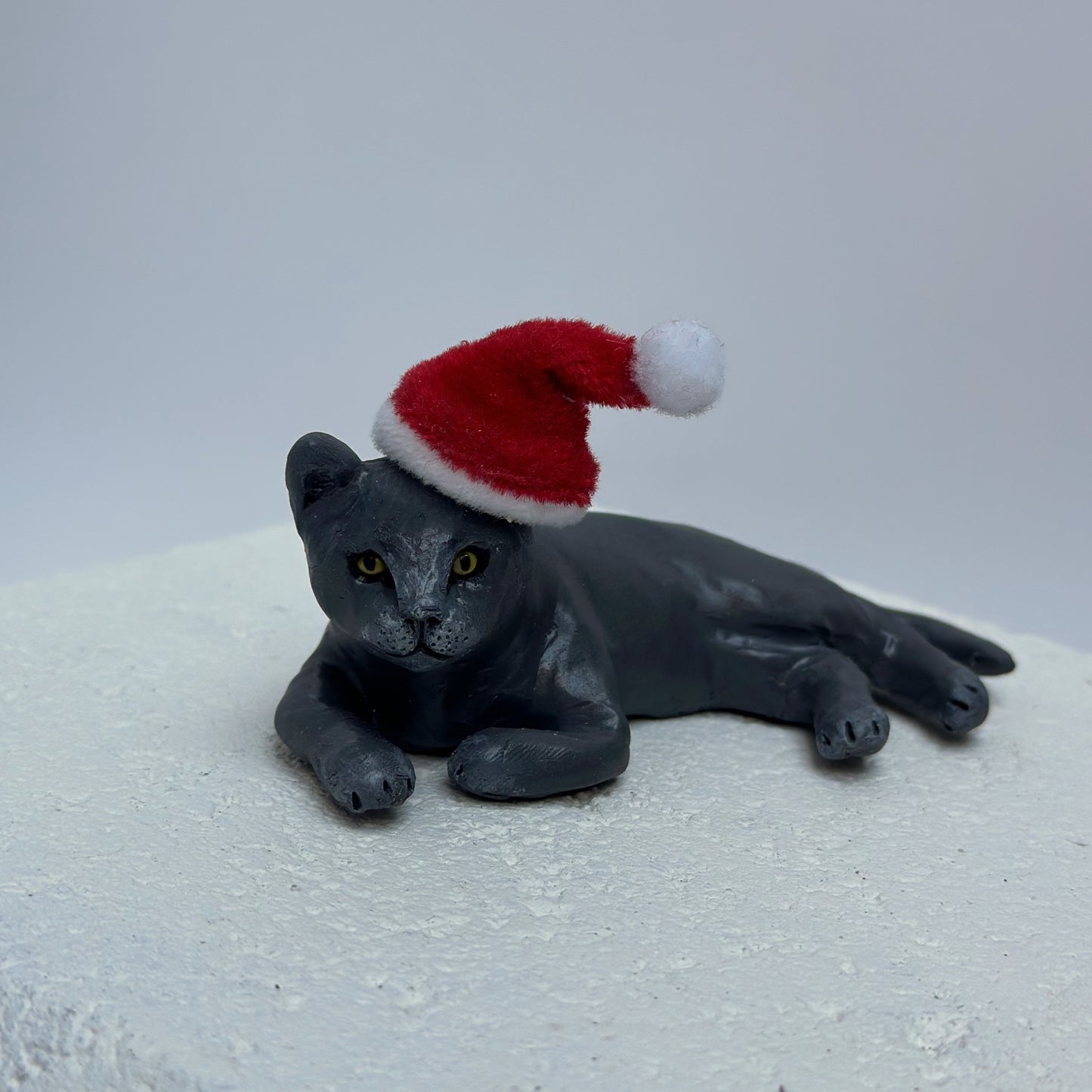 Handmade custom laying grey cat figurine wearing santa hat