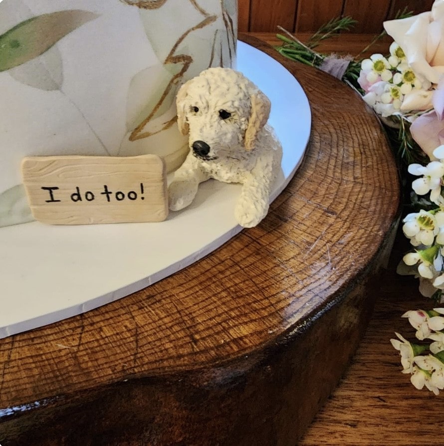 Custom groodle dog peeking topper beside a real wedding cake.
