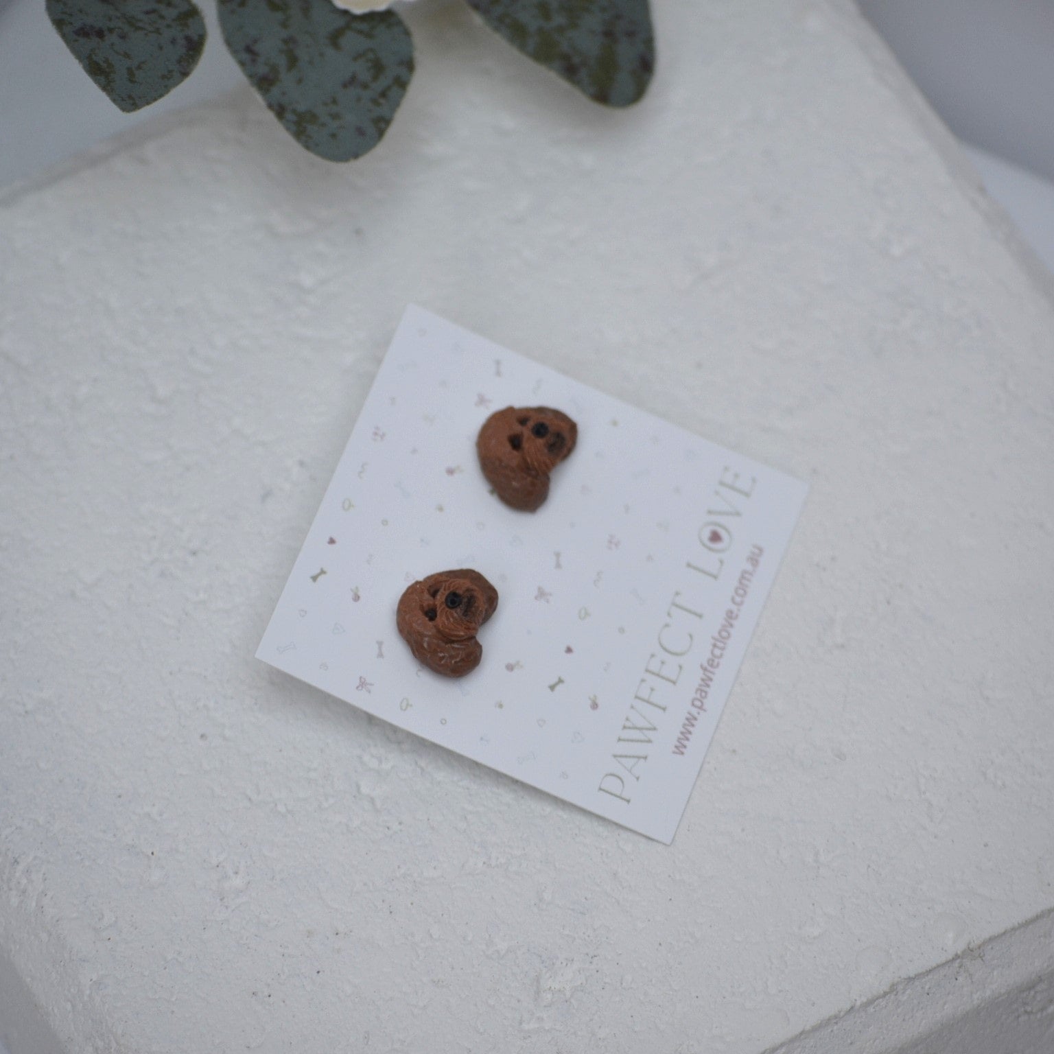 Handmade cavoodle stud earrings by Pawfect Love, positioned in front of white paver