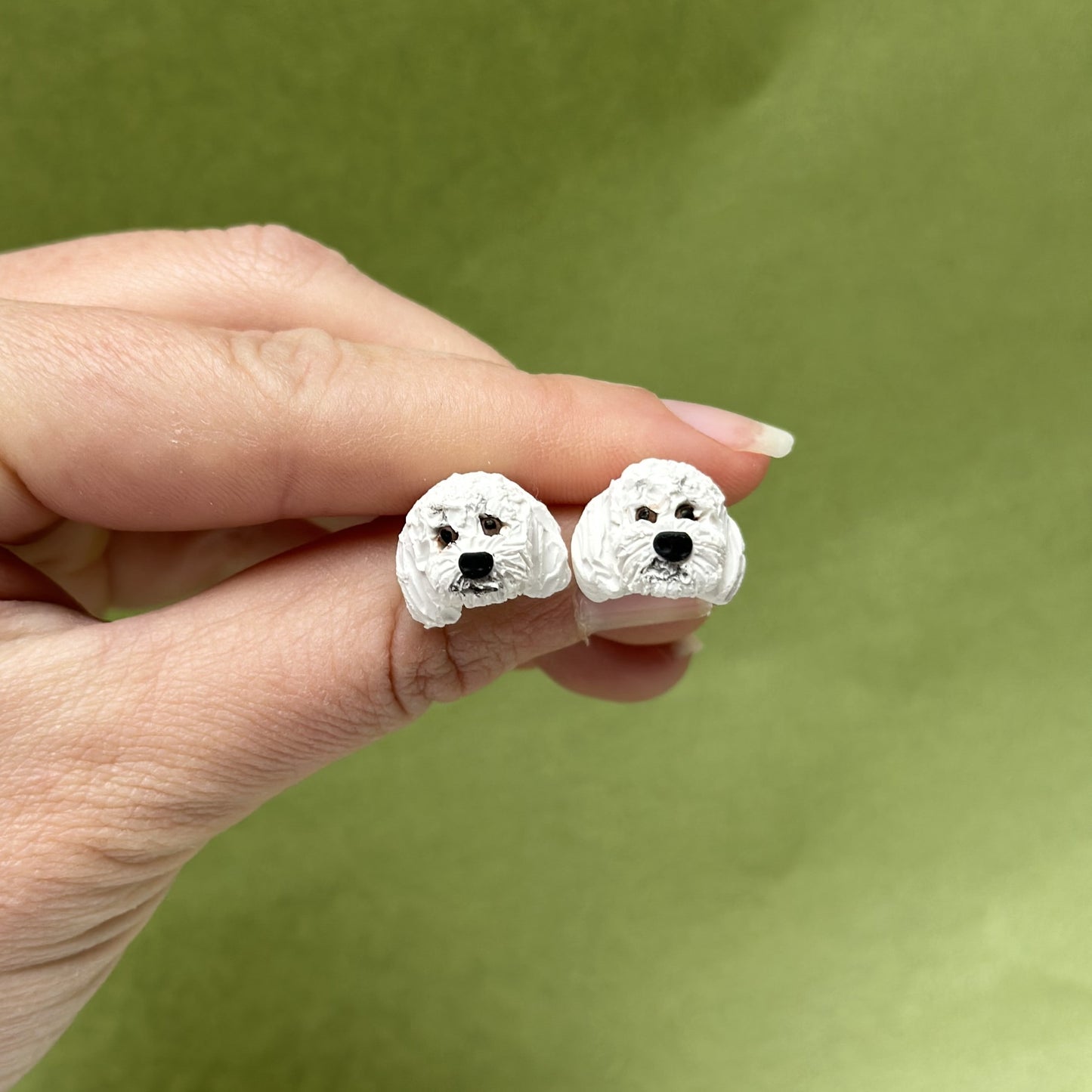 Handmade white poodle stud earrings by Pawfect Love, positioned on green background