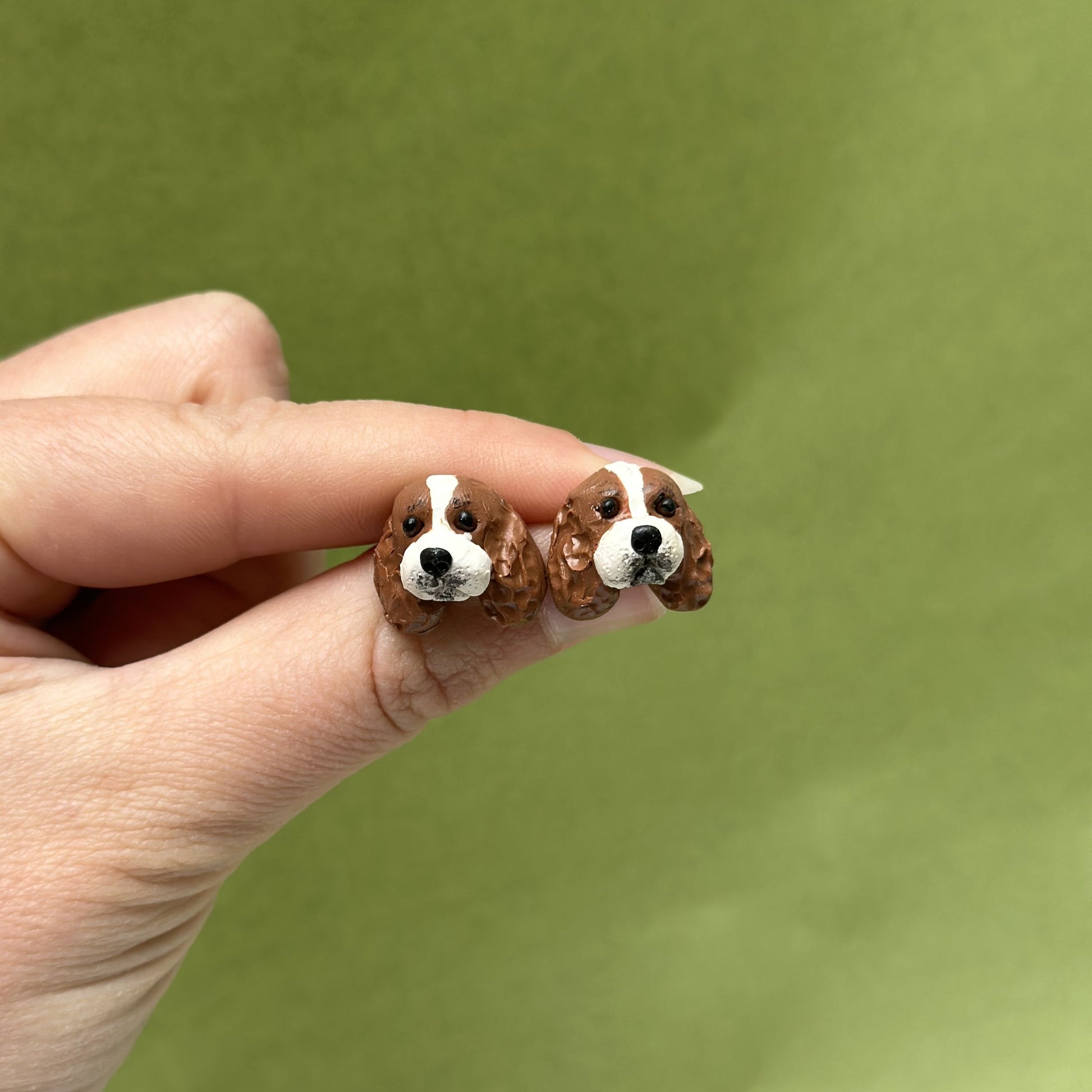 Handmade cavalier king charles spaniel stud earrings by Pawfect Love, positioned in front of green background
