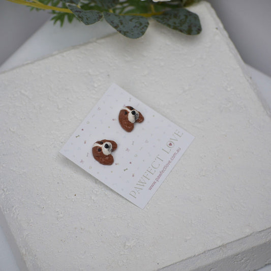 Handmade cavalier king charles spaniel stud earrings by Pawfect Love, positioned in front of white paver