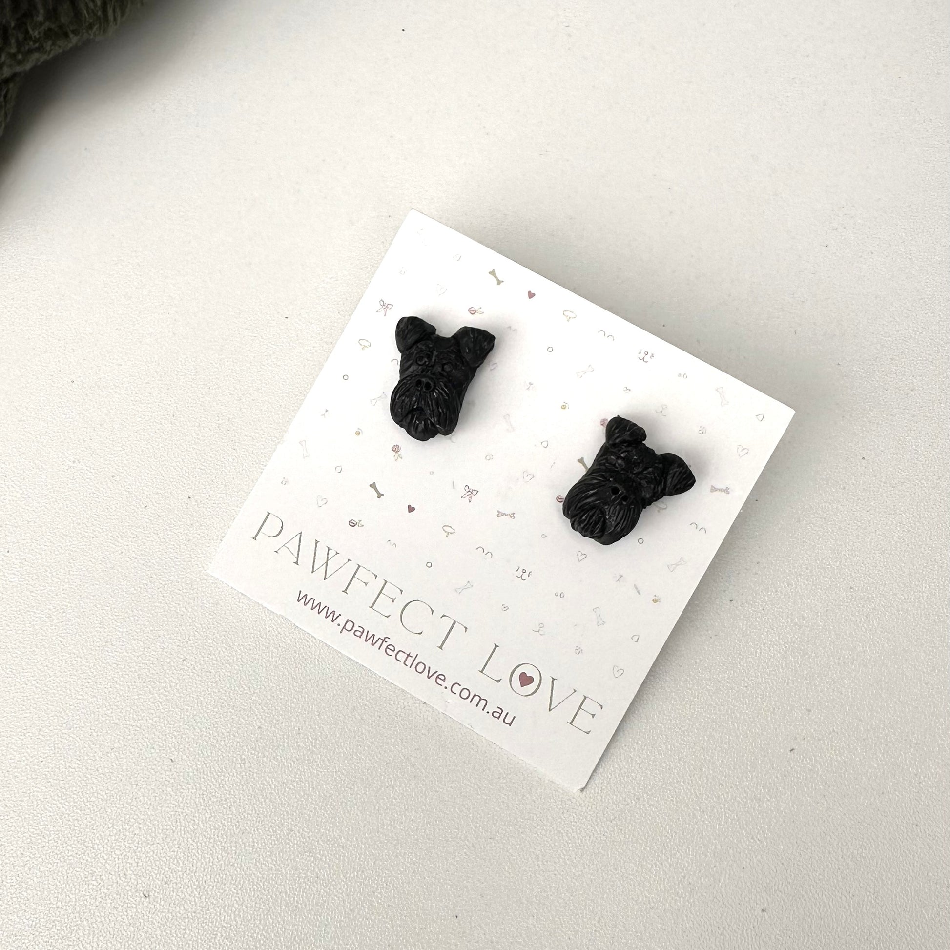 Black schnauzer dog-shaped earrings on a 'PAWfect Love' branded card against a light background