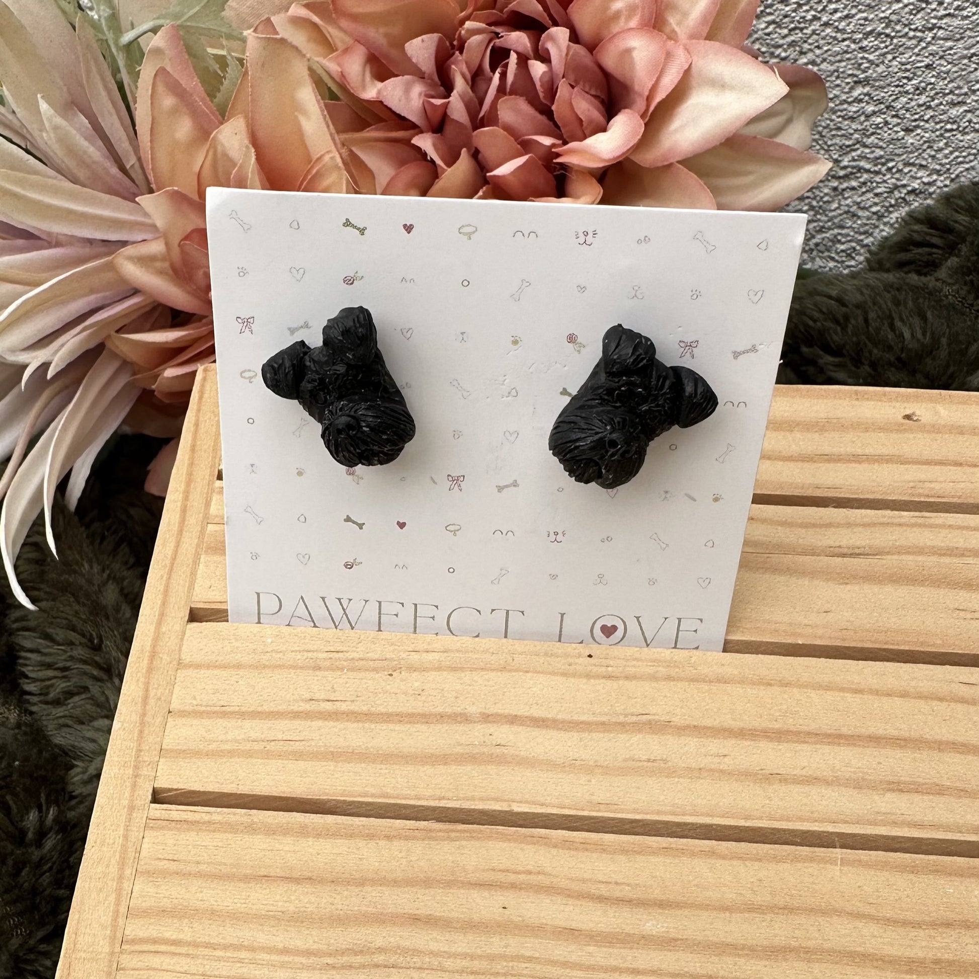 Black schnauzer dog-shaped earrings on a 'PAWfect Love' card with flowers in the background
