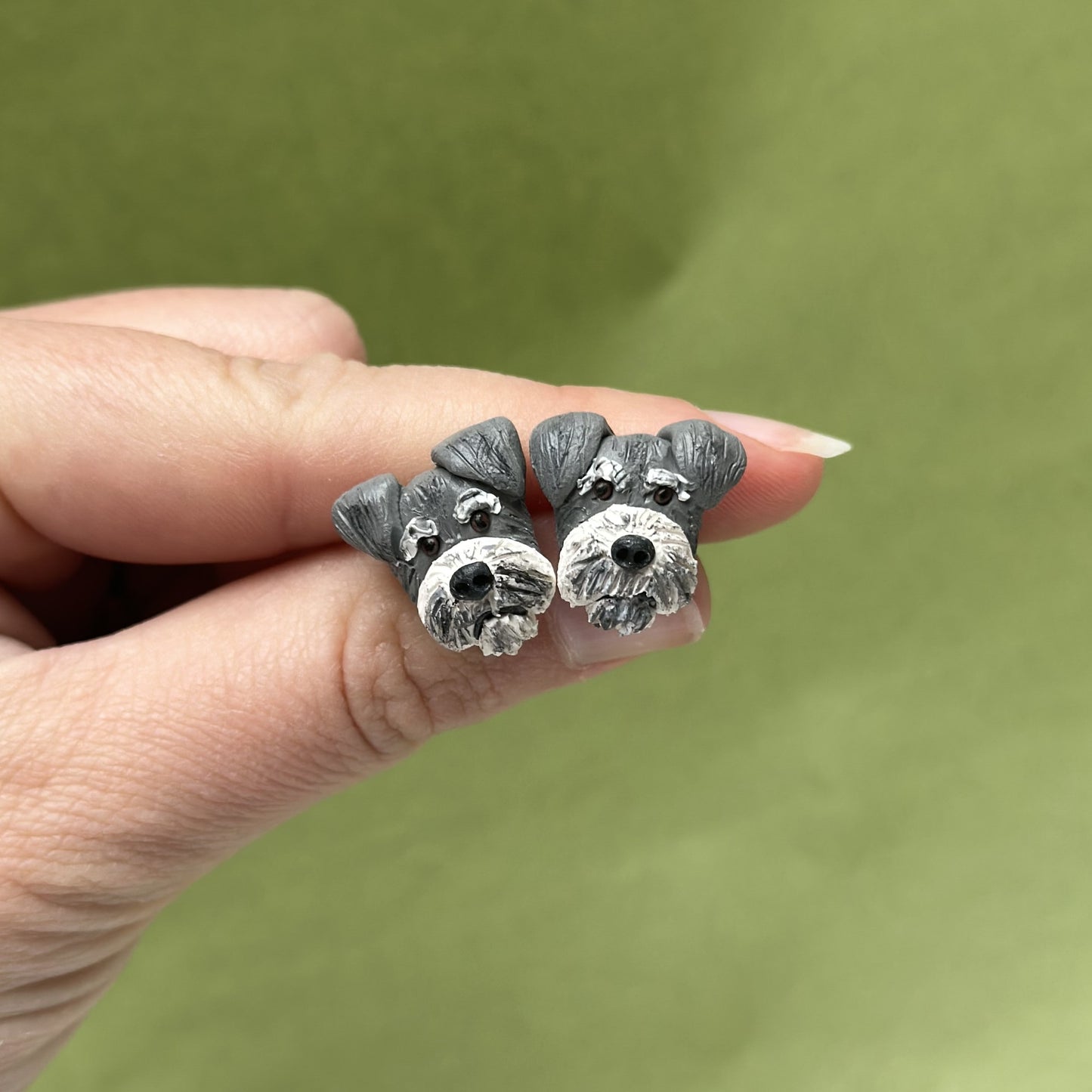 Handmade schnauzer stud earrings by Pawfect Love, positioned in front of green background