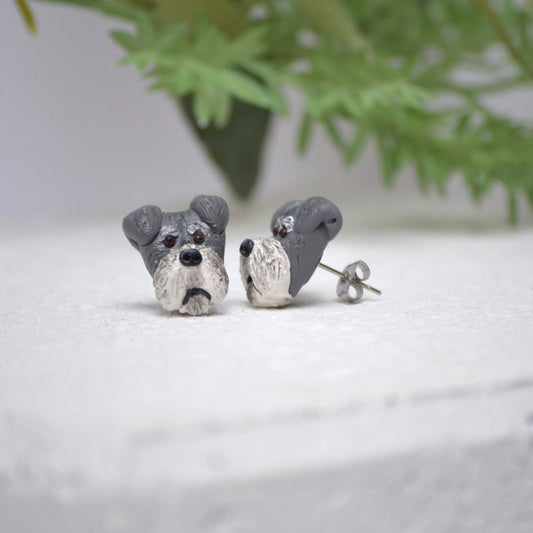 Handmade schnauzer stud earrings by Pawfect Love, positioned in front of green flower arrangement