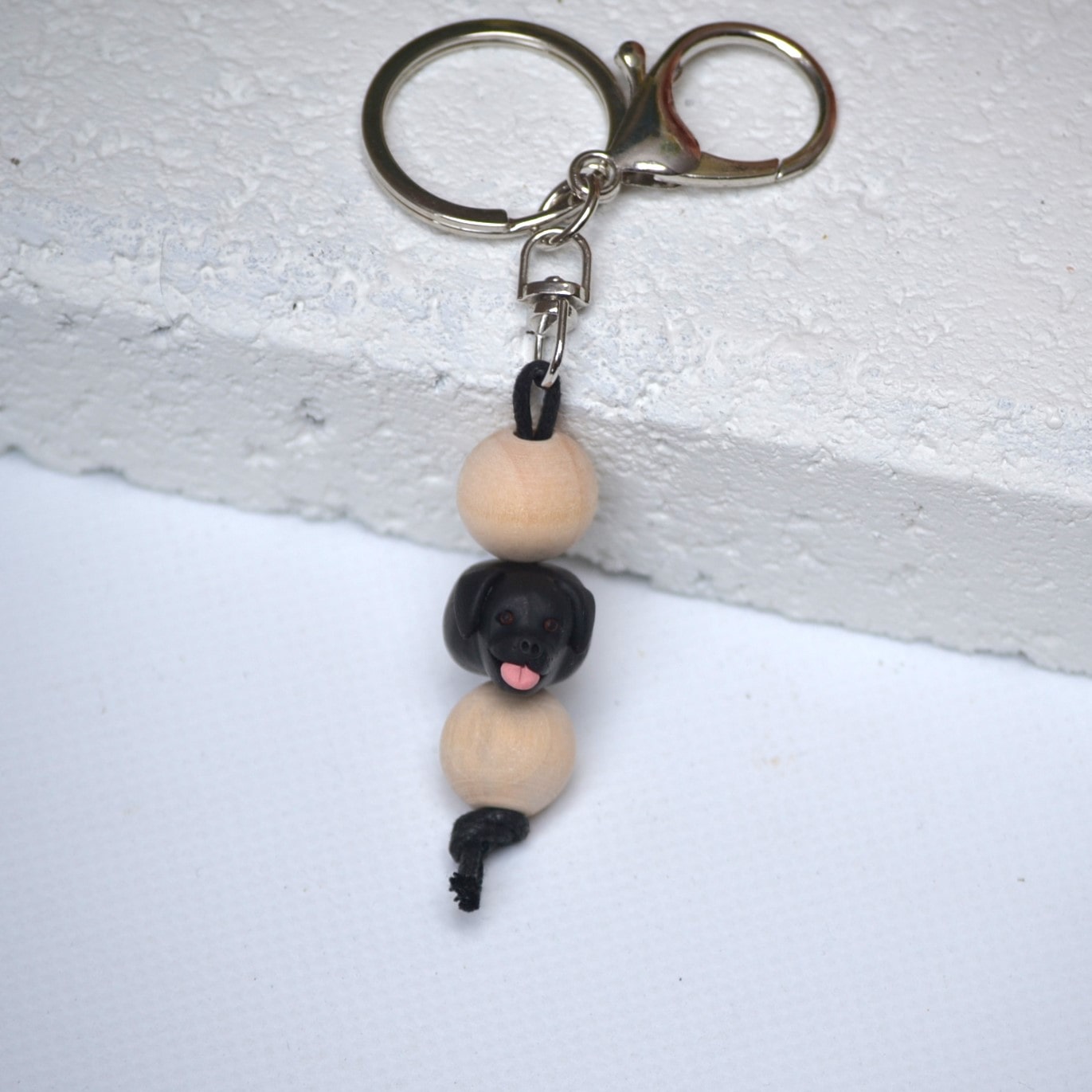 Handmade black labrador dog polymer clay and timber keying on white textured background 