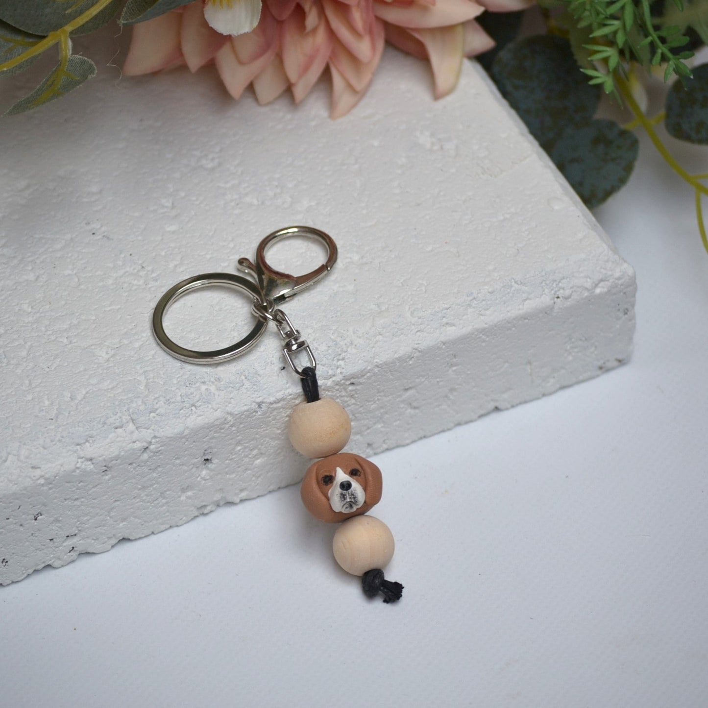 Handmade beagle polymer clay and timber keying on white textured background with a pink flower in the background