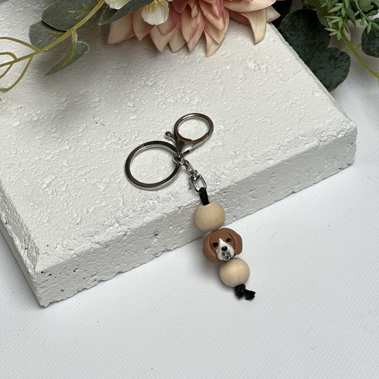 Handmade beagle polymer clay and timber keying on white textured background with a pink flower in the background
