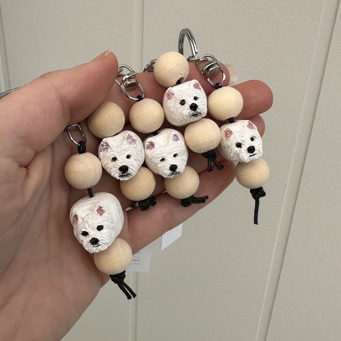 Keychain with Westie dog-shaped beads held by a hand against a neutral background