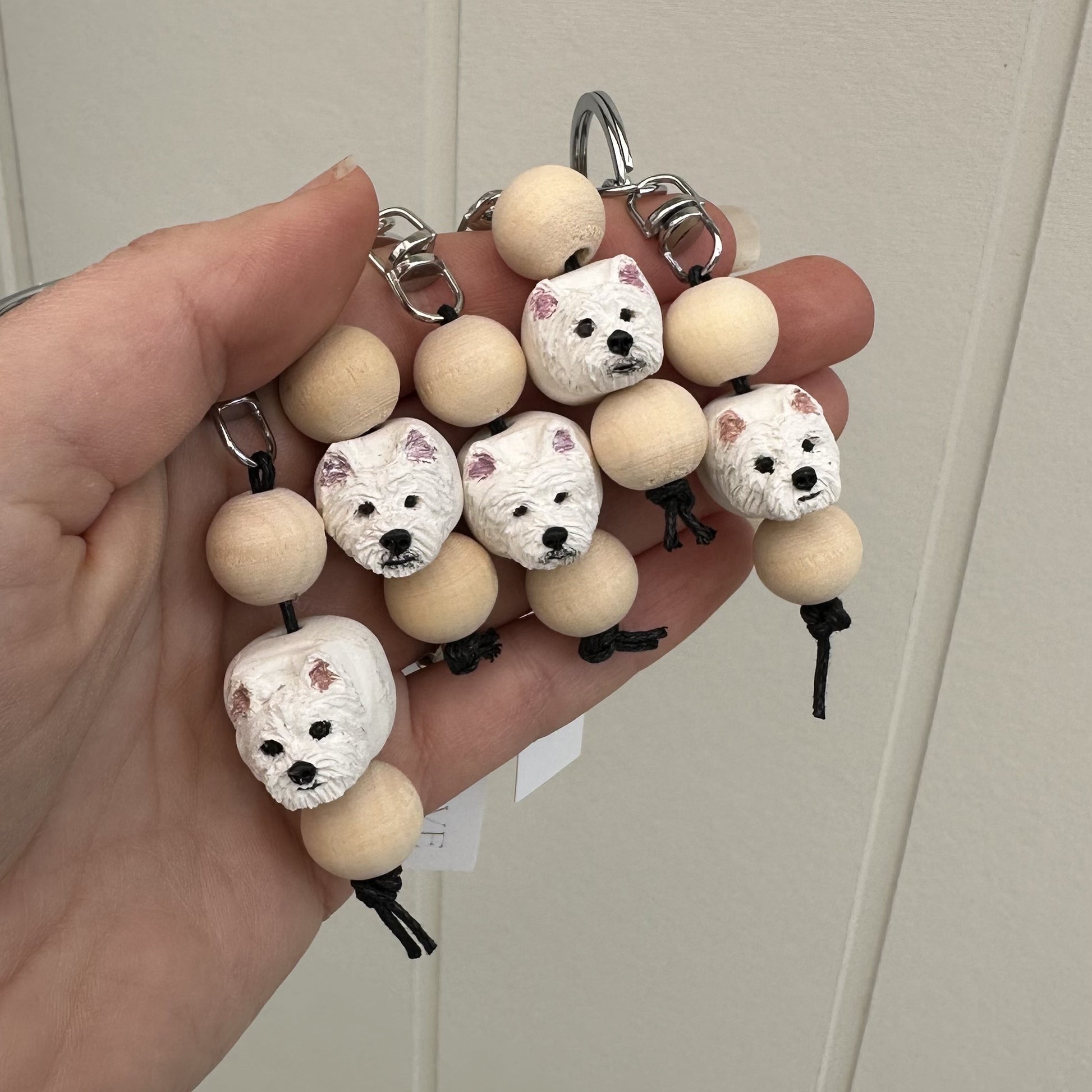 Keychain with Westie dog-shaped beads held by a hand against a neutral background