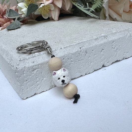 Keychain with a westie dog design on a concrete block with flowers in the background