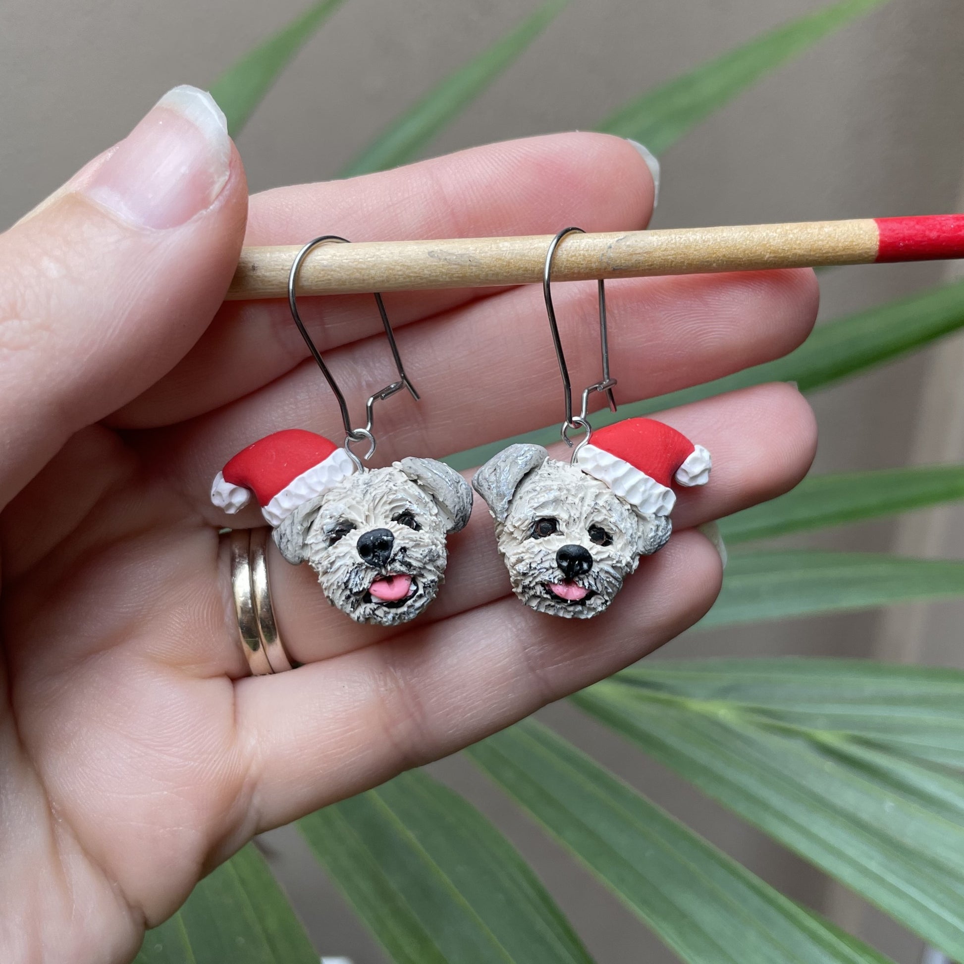 Handmade custom dog dangle earrings wearing santa hats.