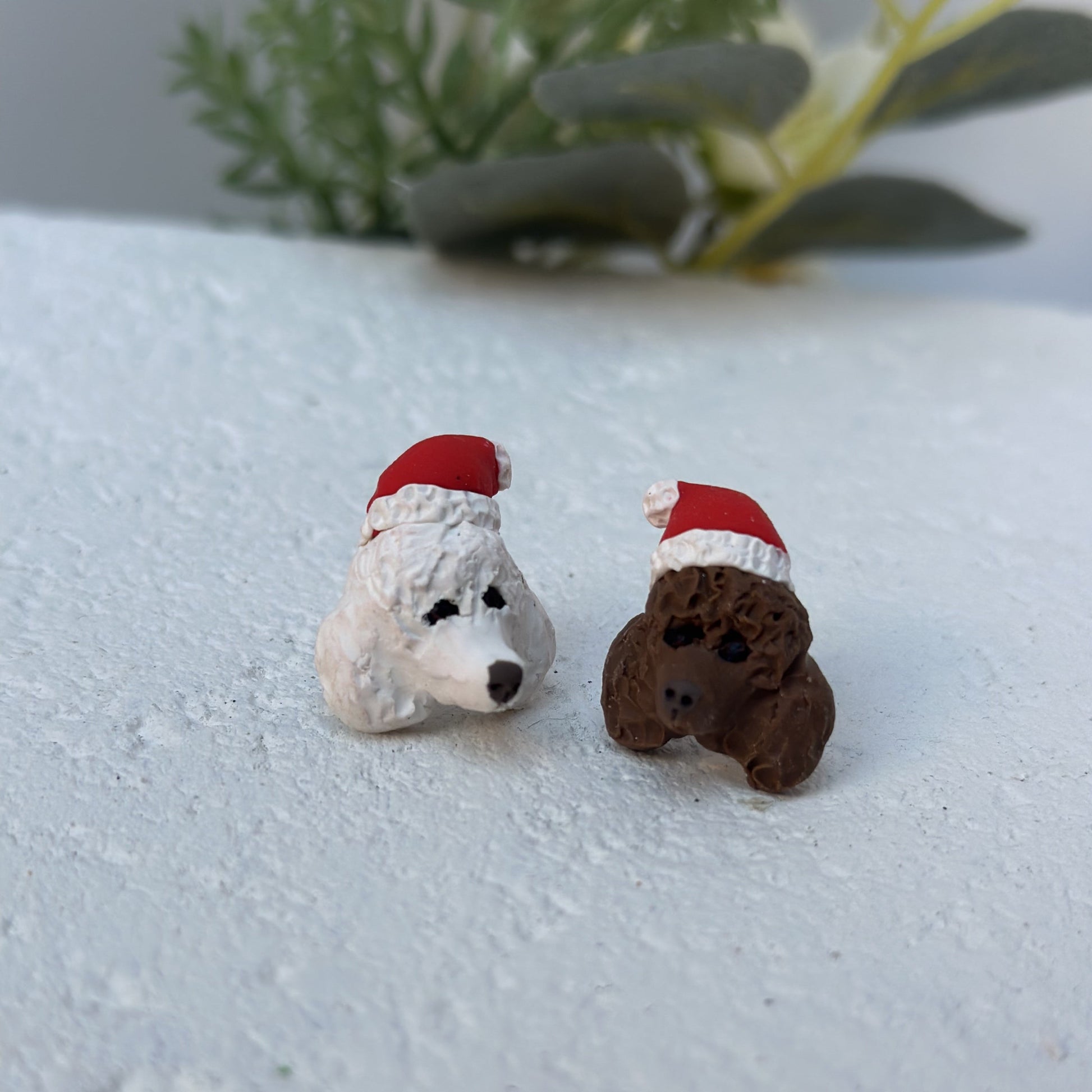 Handmade mismatched custom poodle dog stud earrings wearing santa hats.