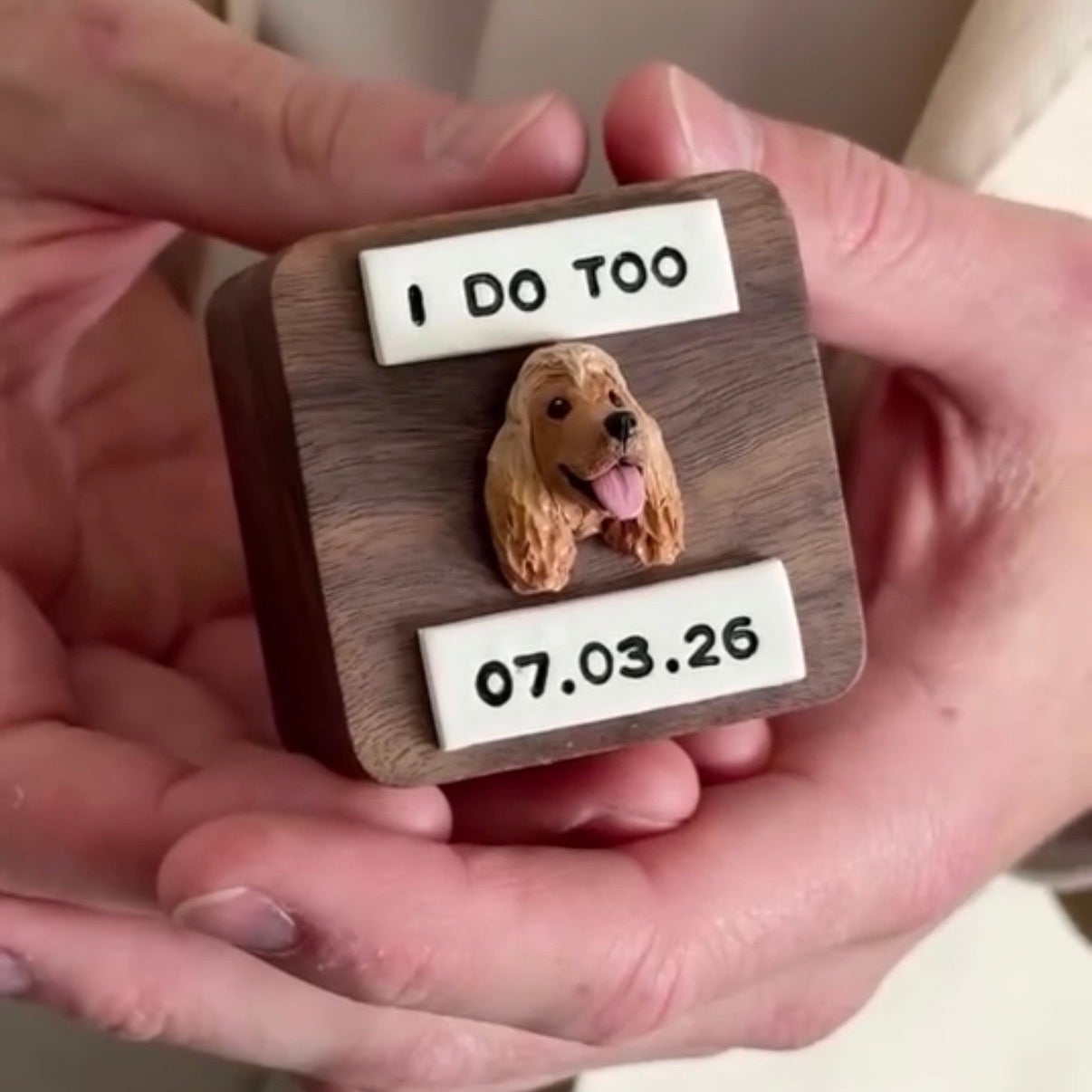 Personalized wooden wedding ring box with a dog illustration and text held in hands.