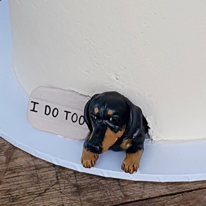 Black and tan dachshund peeking dog wedding cake topper, beside a sign saying I do too.