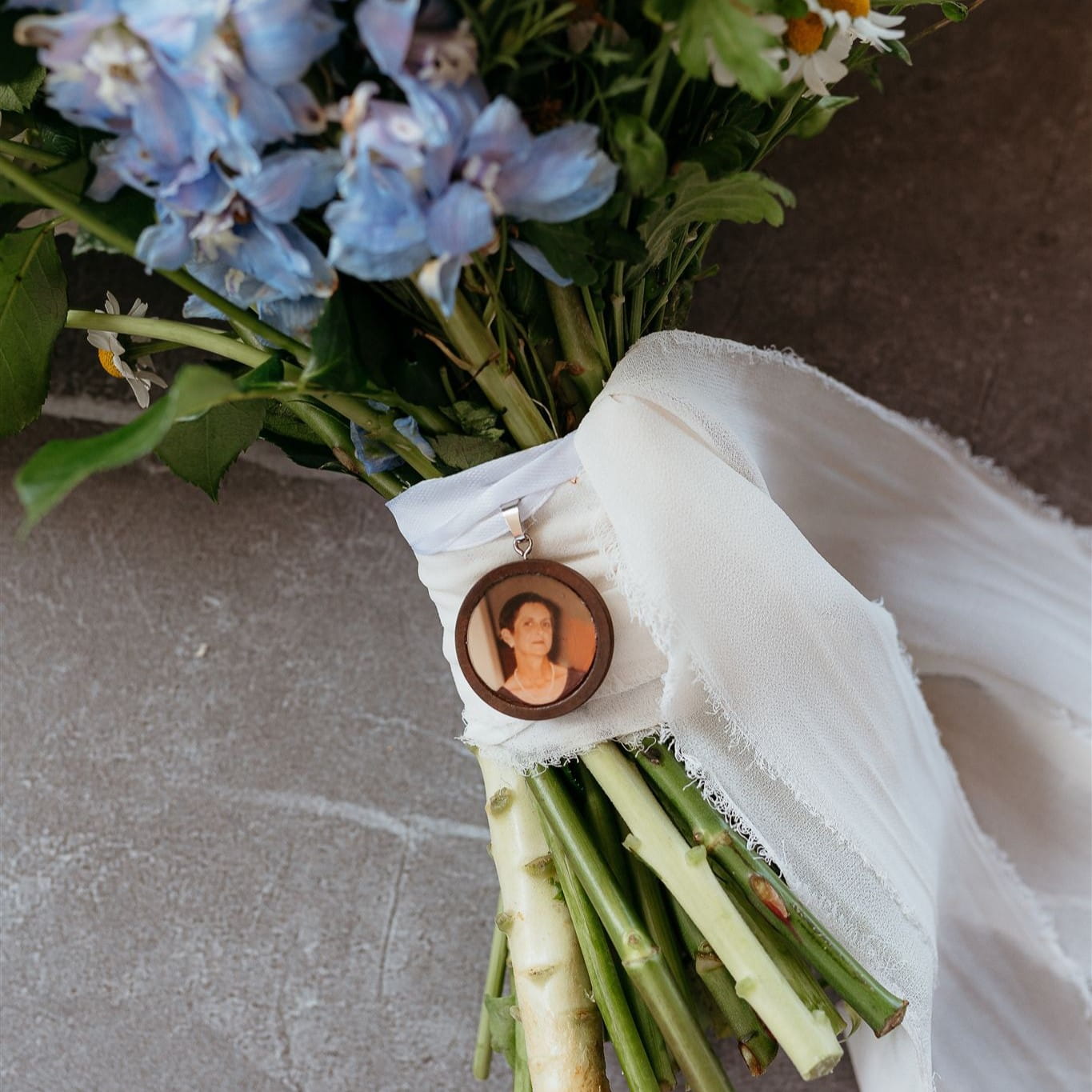 Bouquet of flowers with a portrait pendant on a textured surface