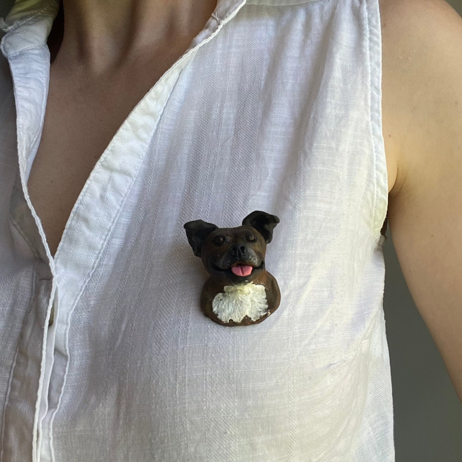 Handmade custom pet face brooch showing a brindle staffy's face, being worn on a white shirt.