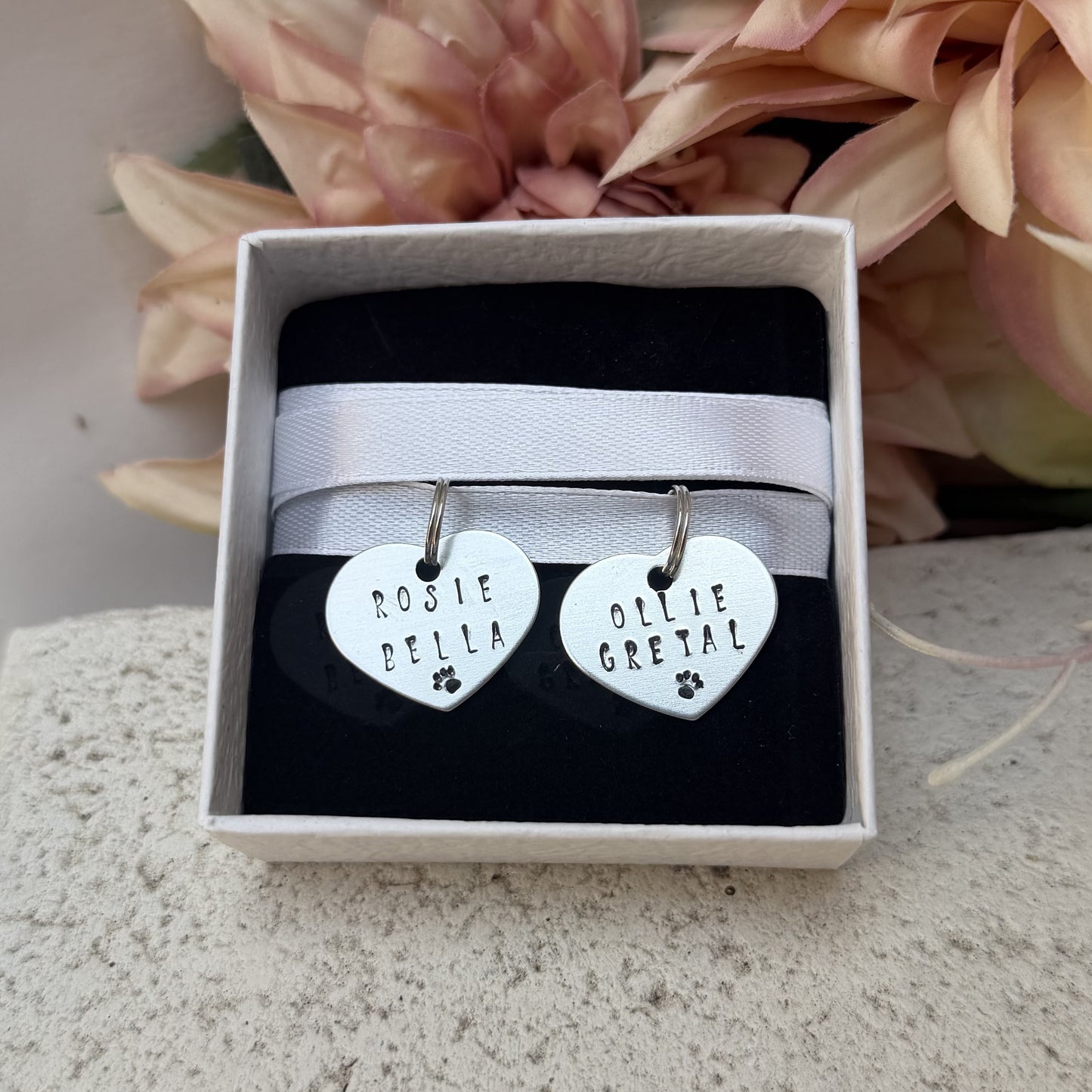 2 packaged metal stamped hearts with pet names on ready to be placed on wedding bouquet.