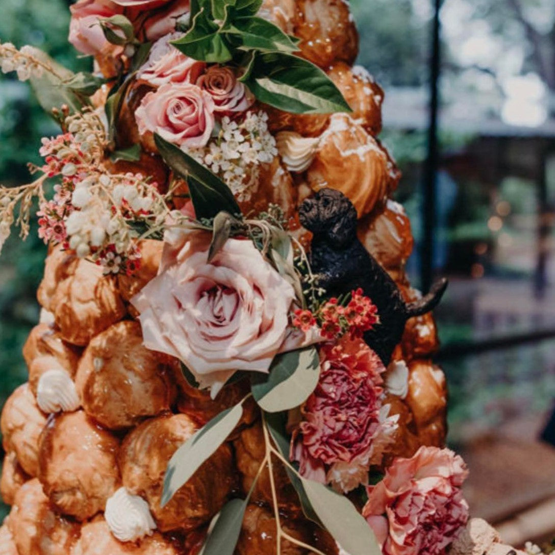Black poodle cake topper climbing a croquembouche wedding cake.