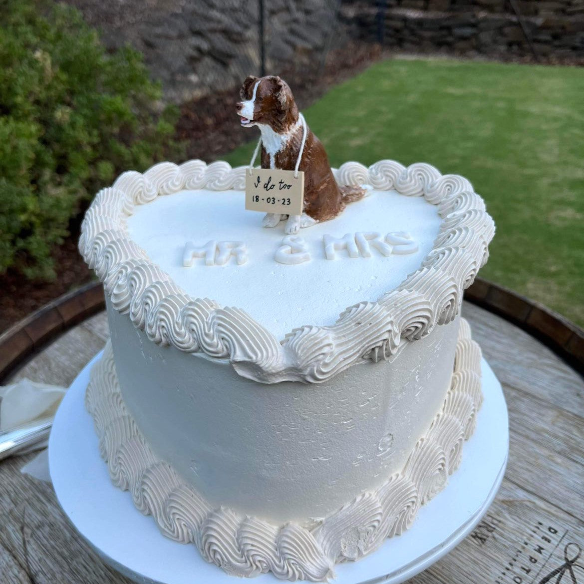 Brown border collie handmade custom dog cake topper on a heart shaped cream wedding cake showing the letters Mr & Mrs.