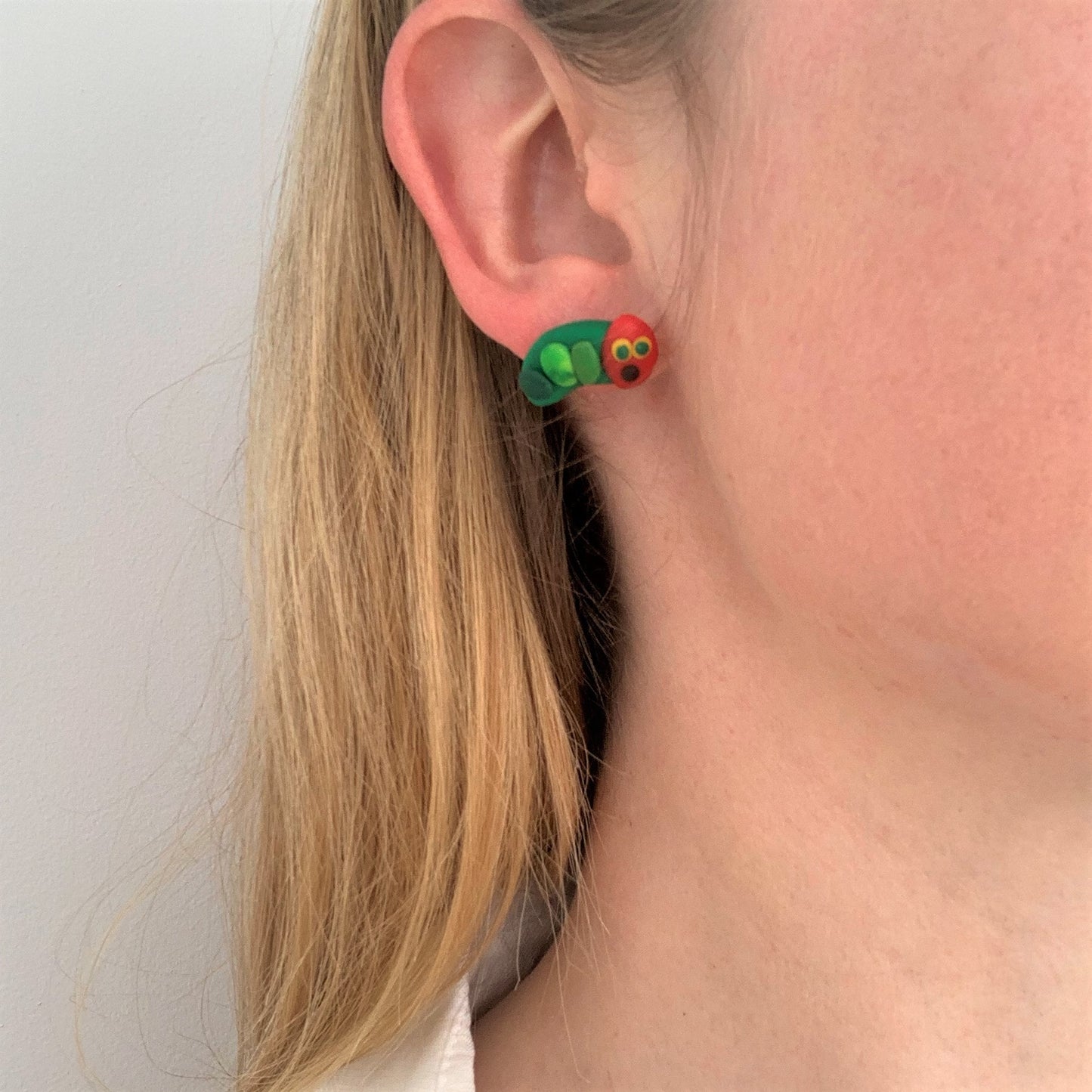 Caterpillars stud earrings by Heartbeat Handicrafts being worn on model's ear