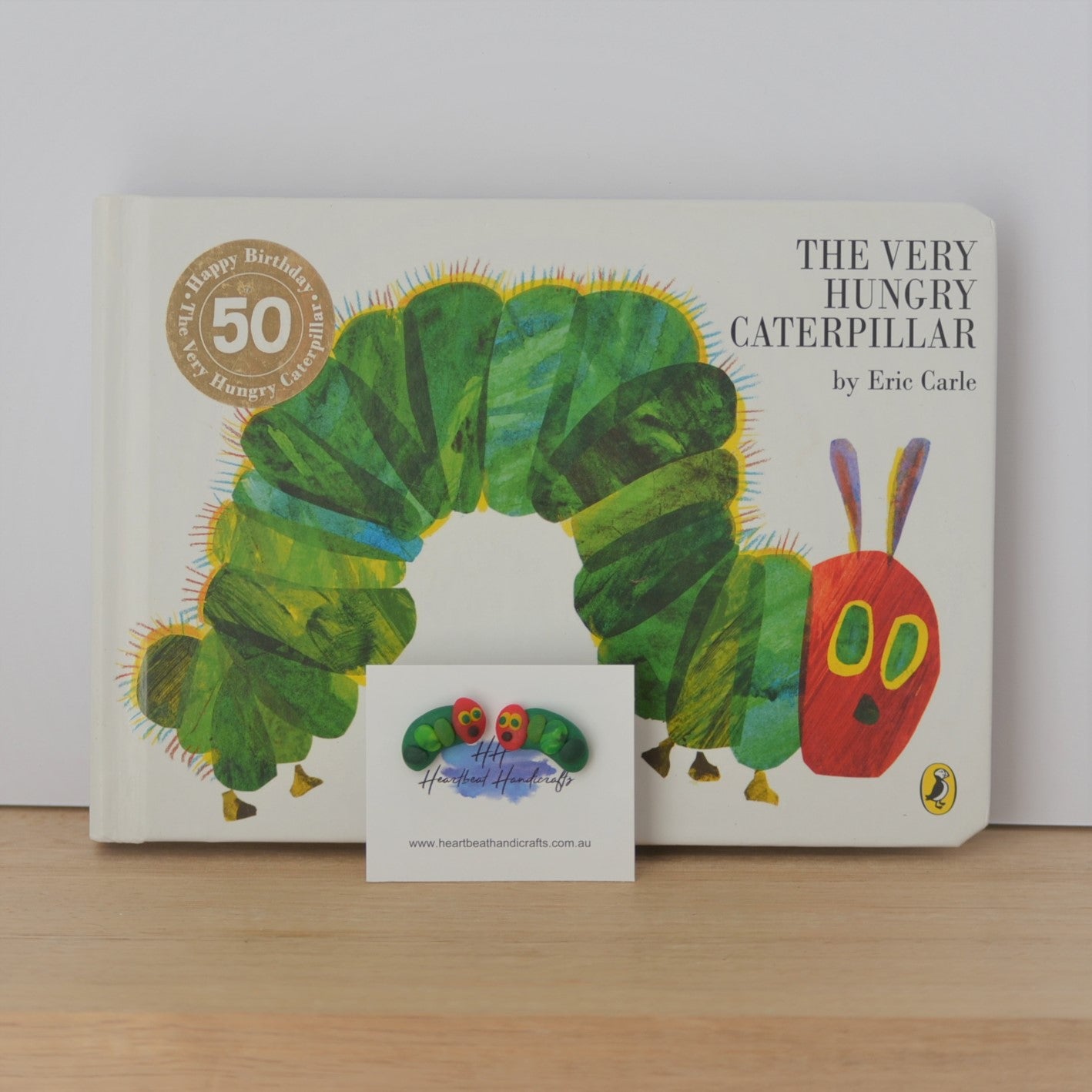 Caterpillar stud earrings shown in front of The Very Hungry Caterpillar book