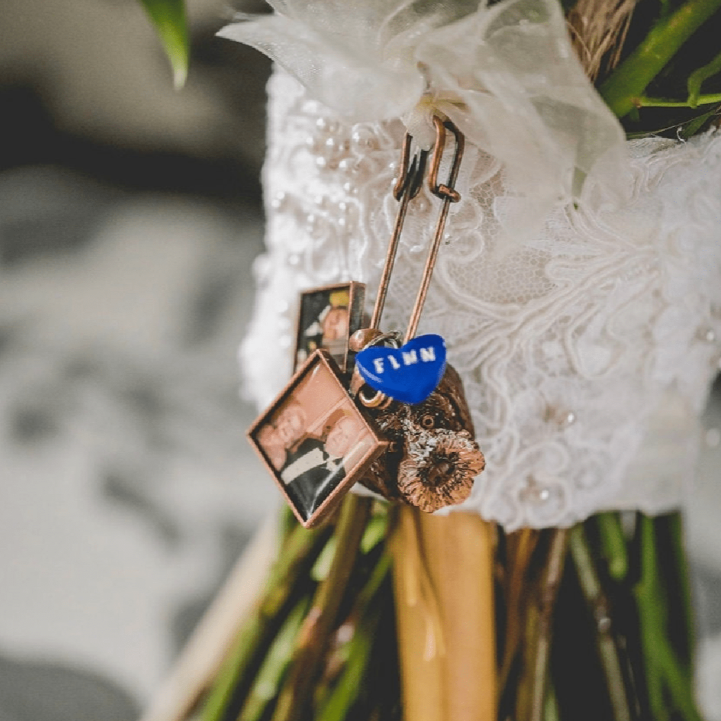 Custom pet bridal bouquet charm photo from a wedding day, featuring a dog face and a blue heart name charm..