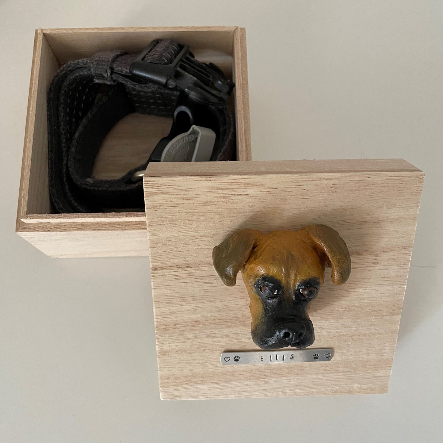 Custom timber pet memorial keepsake box with handscultped dog face on the lid, with a name plaque reading Ellis. Box is open showing collar being stored within,