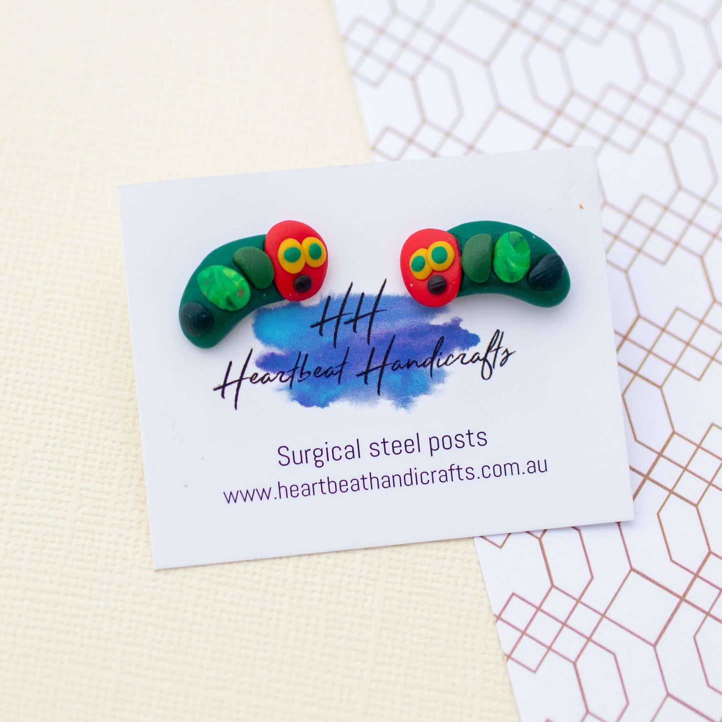 Caterpillar stud earrings shown on earrings card on paper background