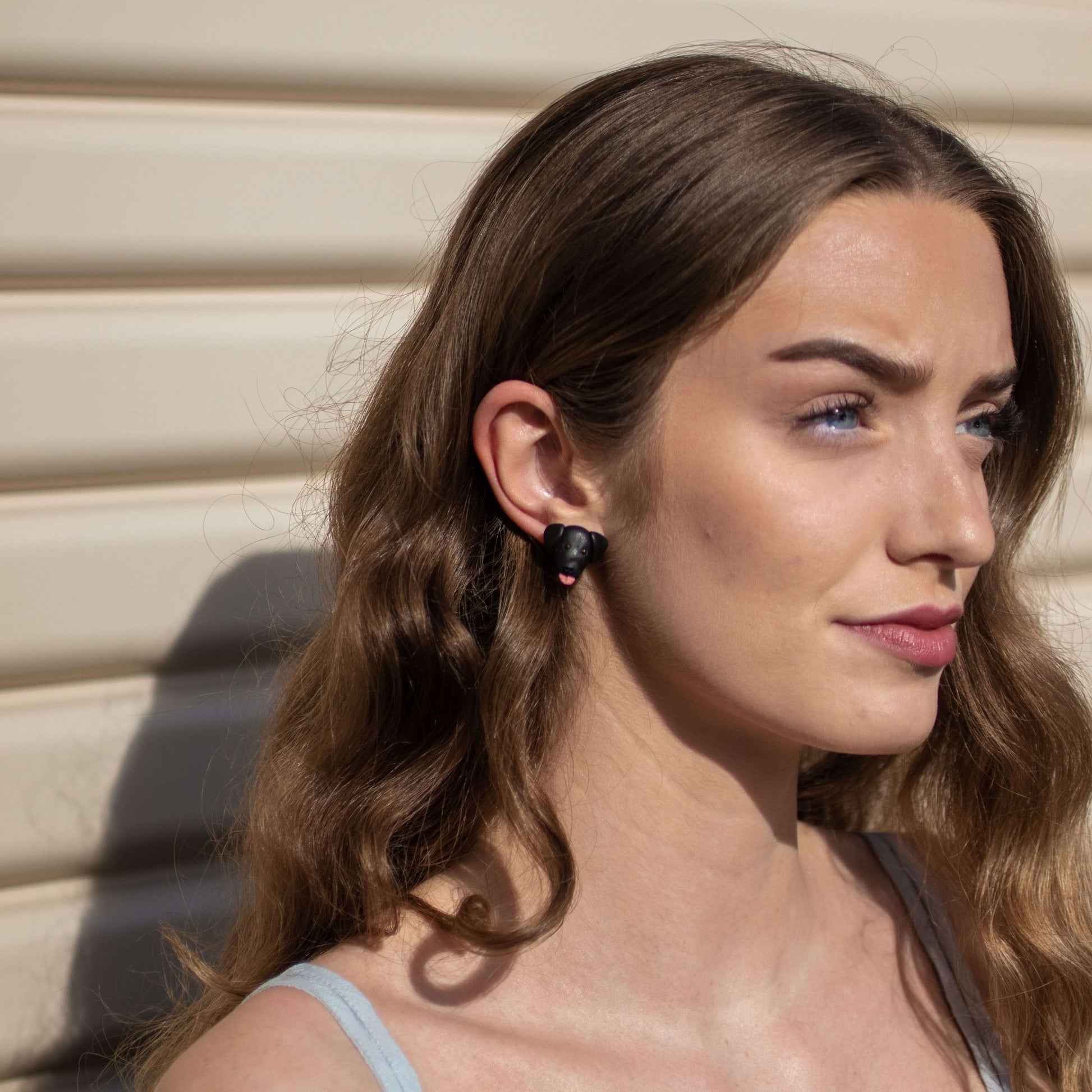 Handmade polymer clay black lab stud earrings on model's ear