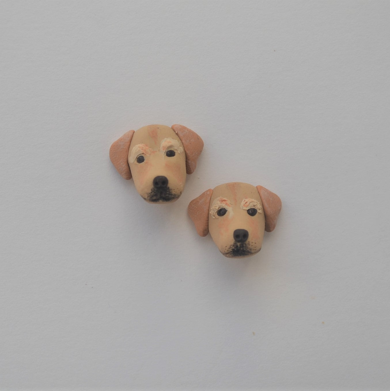 Handmade polymer clay golden lab retriever stud earrings shown offset on white background