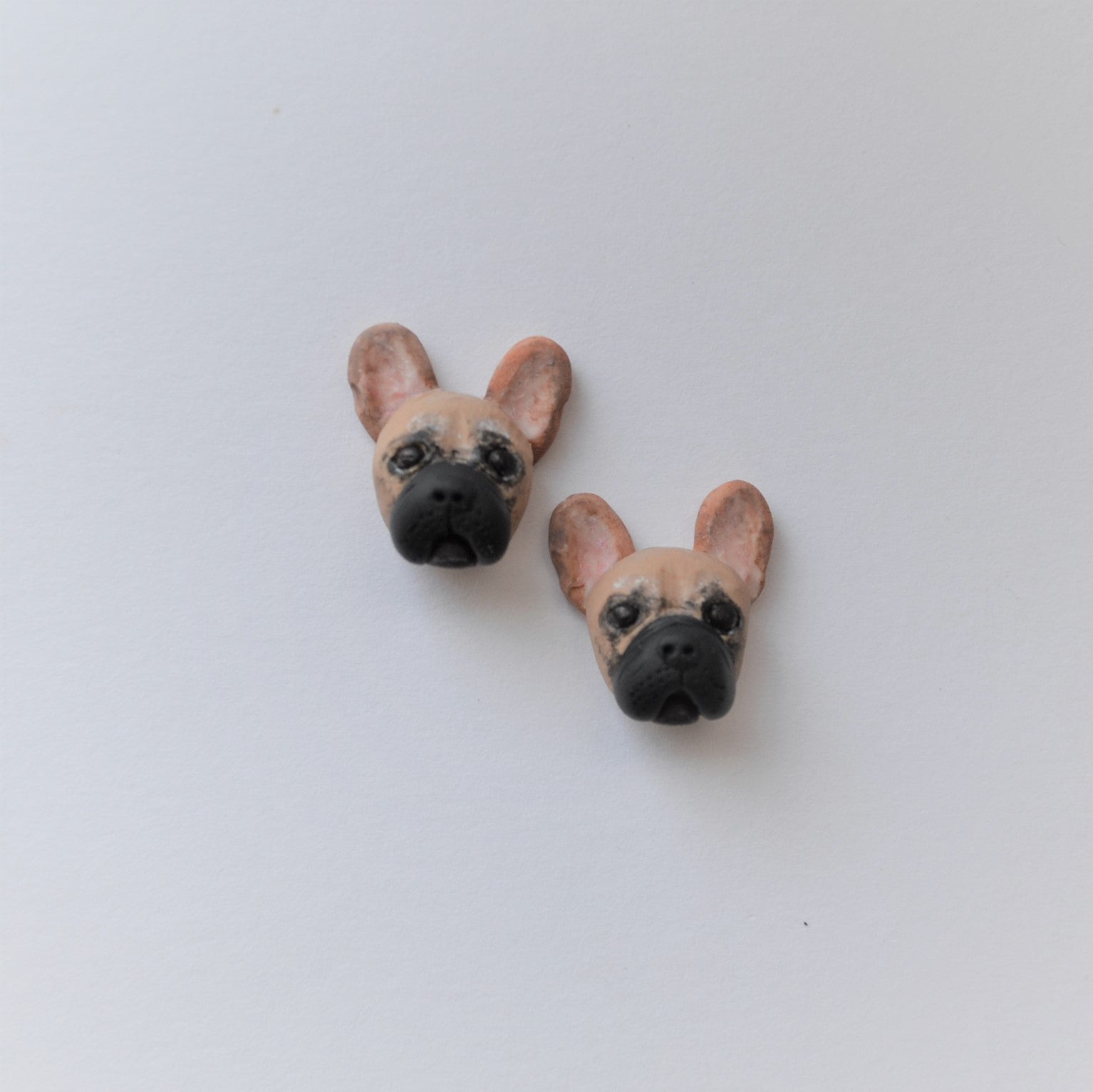 Handmade polymer clay french bulldog stud earrings shown offset on white background