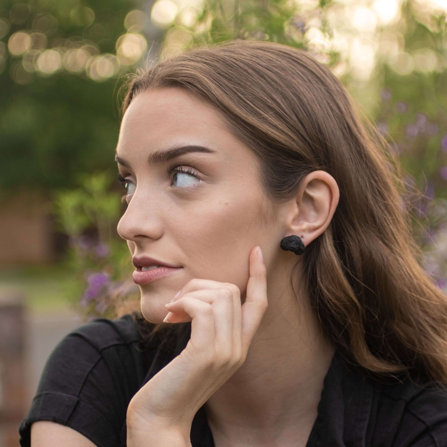 Handmade polymer clay black poodle stud earrings shown on model's ear