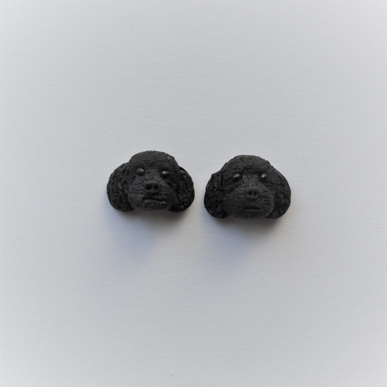Handmade polymer clay black poodle stud earrings shown on white background