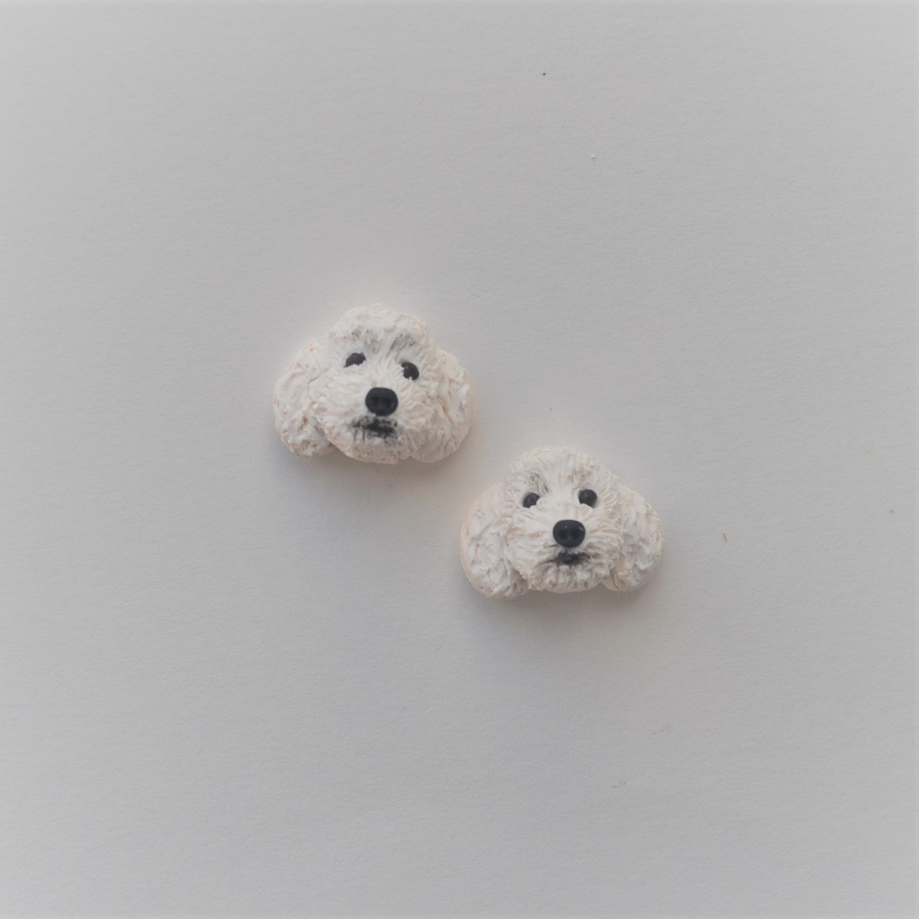 Handmade polymer clay white poodle stud earrings shown offset on white background