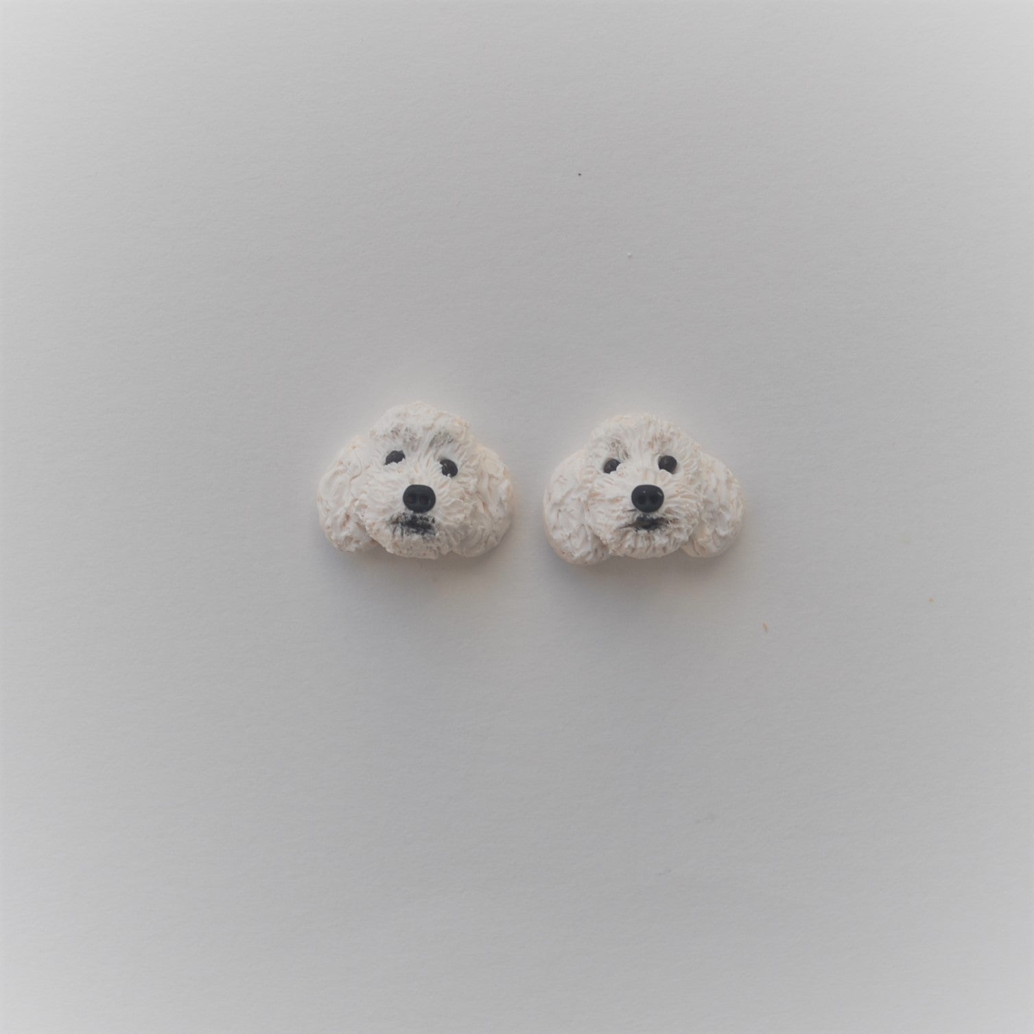Handmade polymer clay white poodle stud earrings shown on white background
