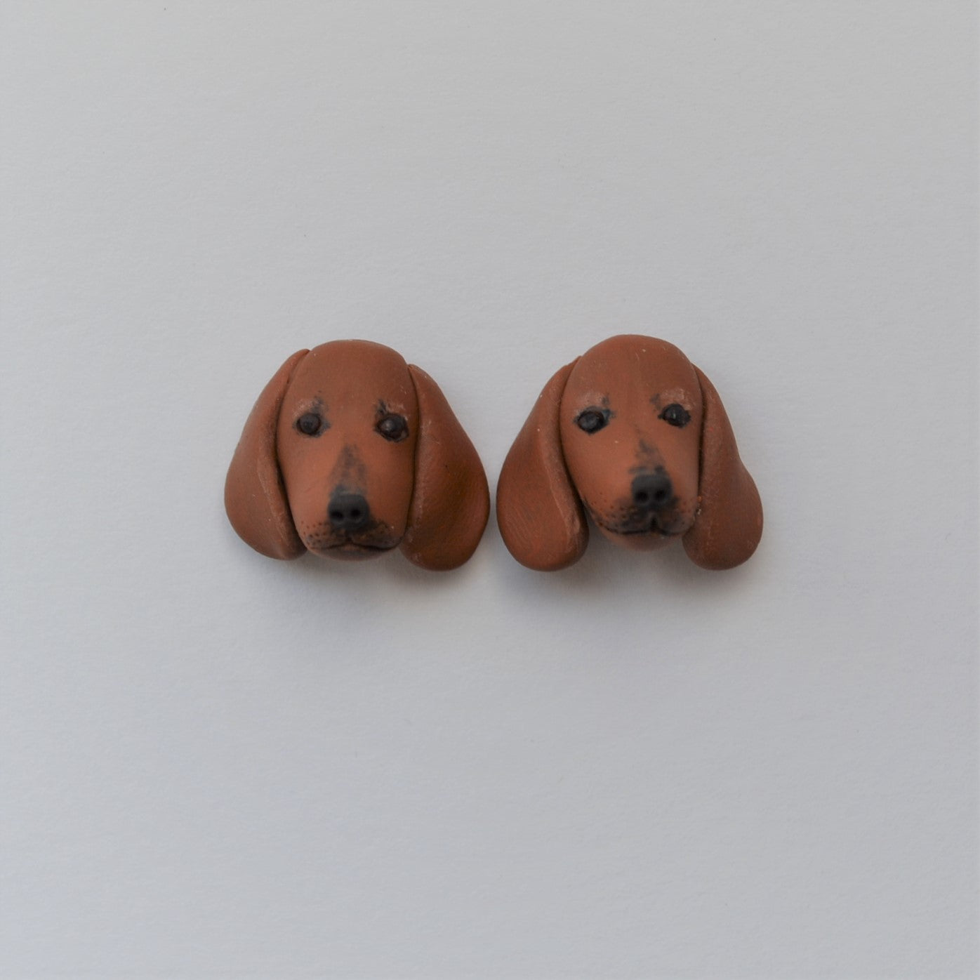 Handmade polymer clay Dachshund stud earrings shown on white background