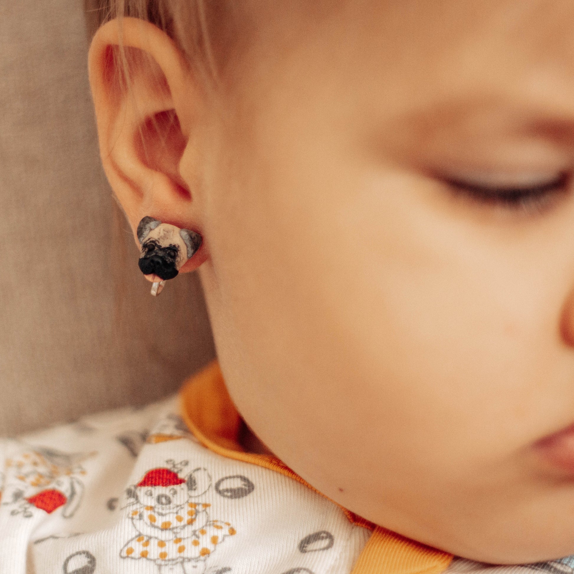 Clip-on custom pug dog earrings being worn by a small child.
