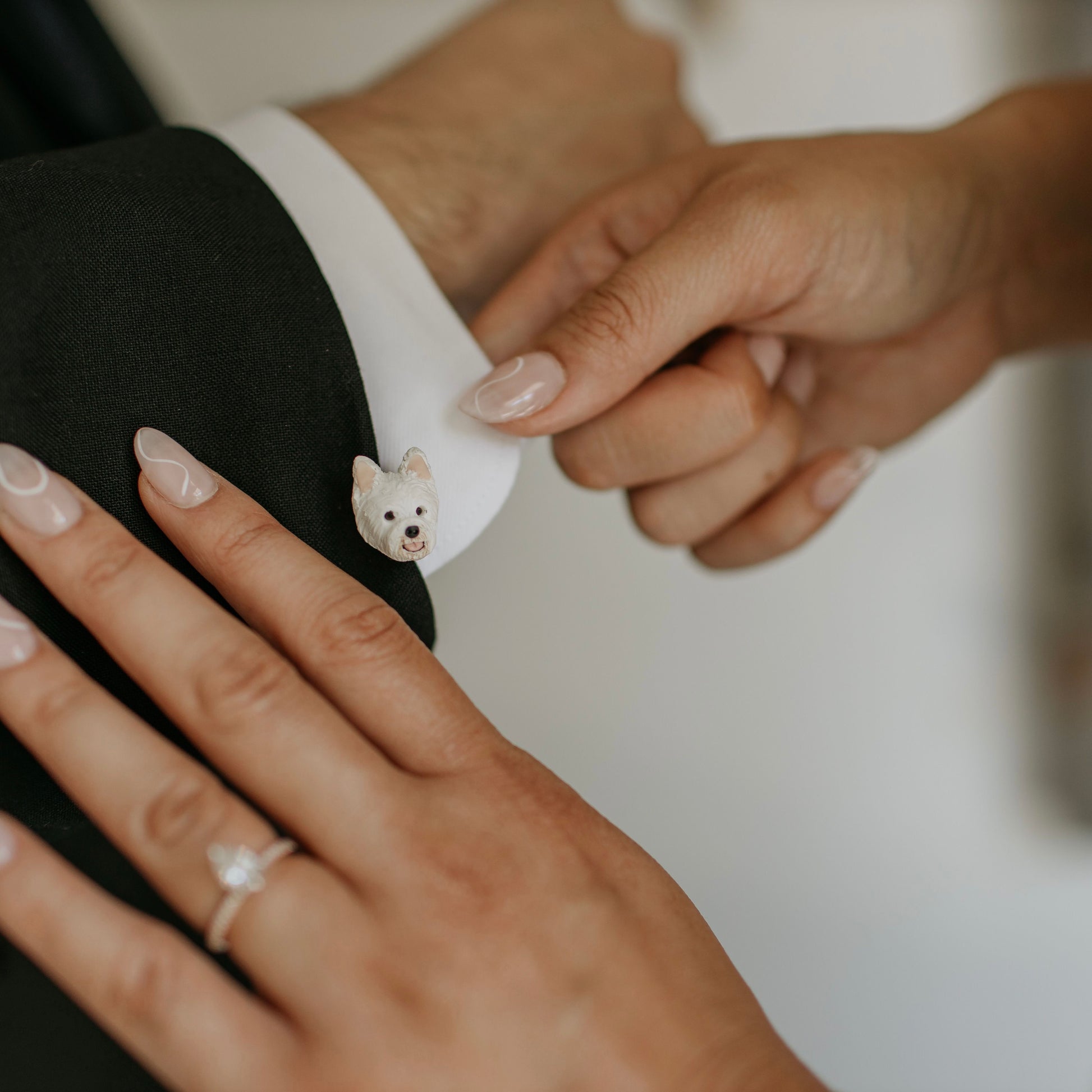 Custom westie dog cufflinks being adjusted by a bride on the groom's sleeve.